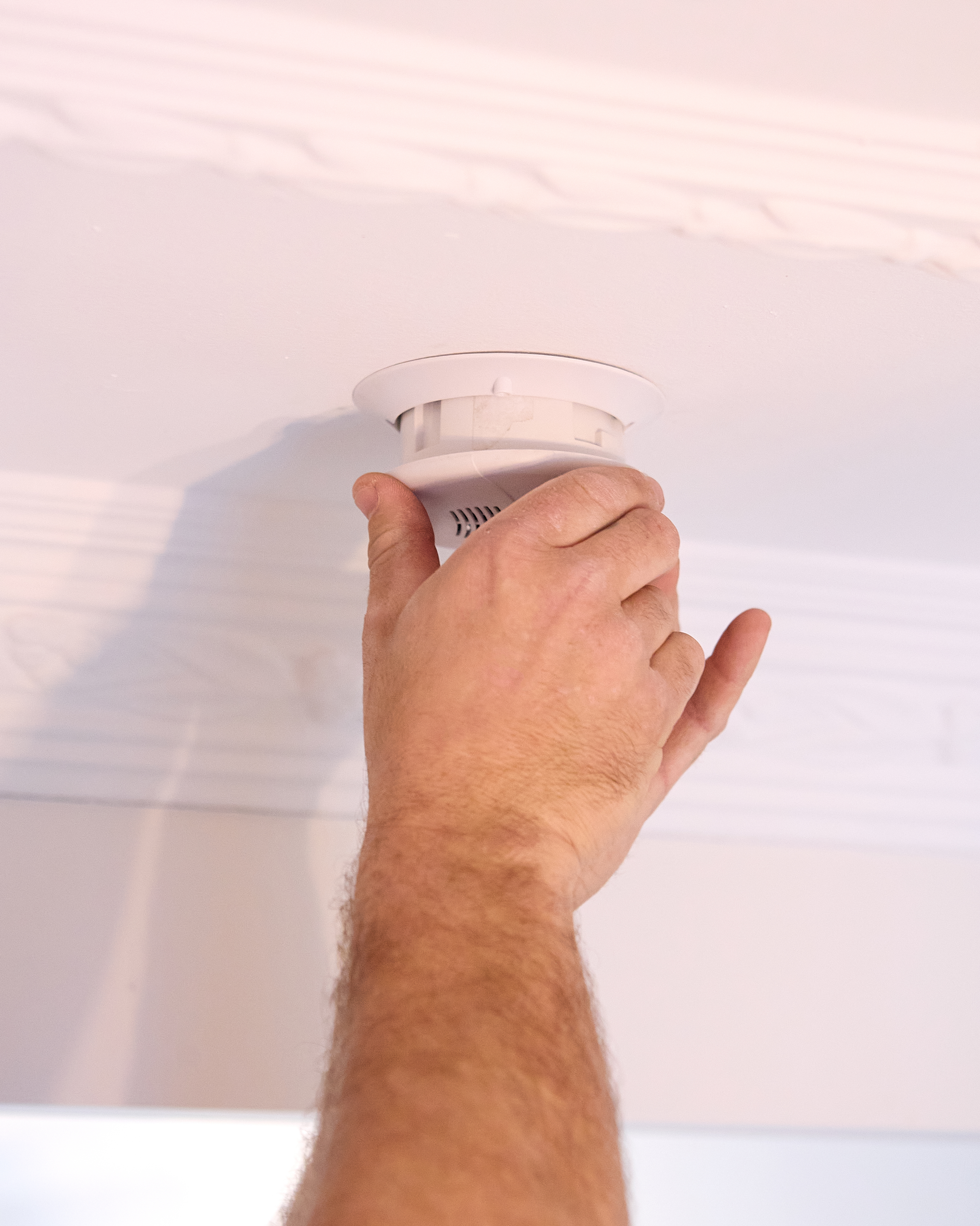 Technician testing a ceiling-mounted smoke alarm
